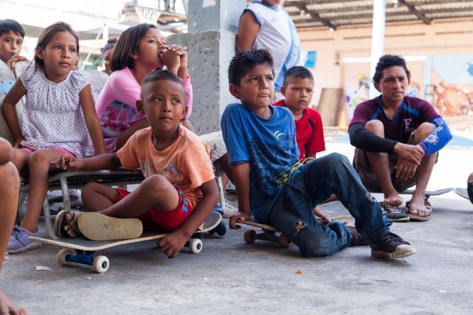 Children sit and listen at a skate park