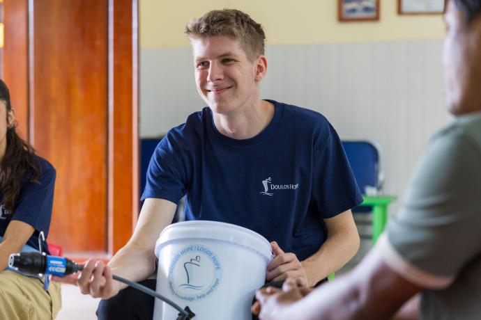 Sihanoukville, Cambodia :: Jonte (Germany) smiles as he presents the water bucket to a local community centre.