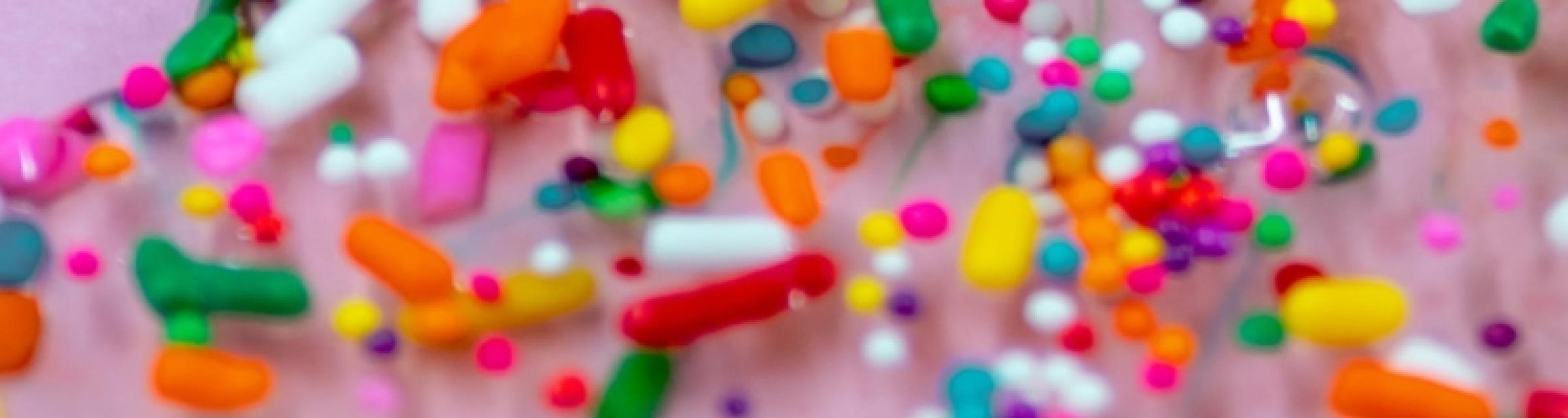 Bunte Bonbons und andere Teilchen auf rosa Hintergrund