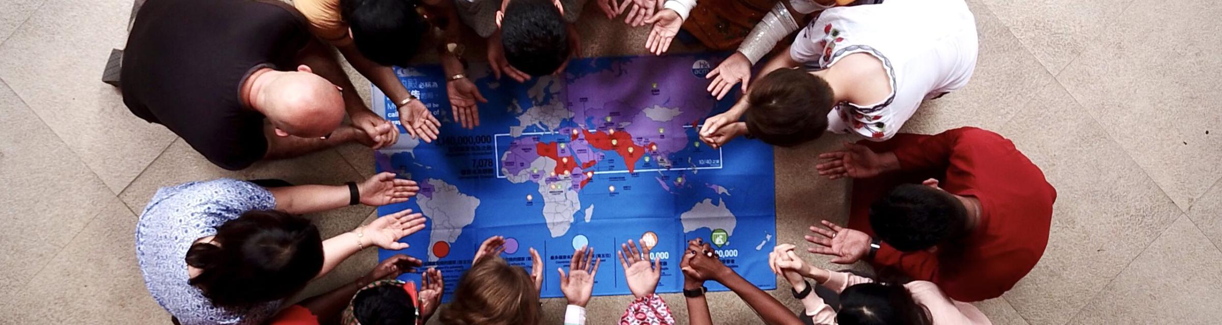 Eine Gruppe Menschen betet über einer Weltkarte