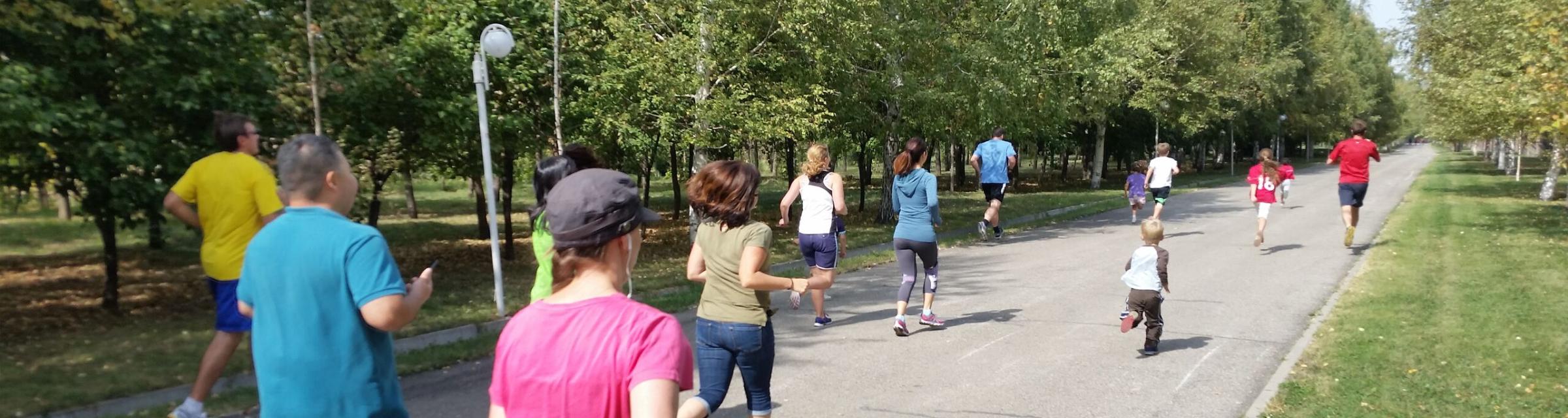 A dozen people of various ages run through a Central Asian park.