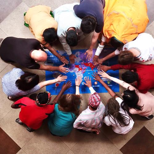 different people pray over a map of the world