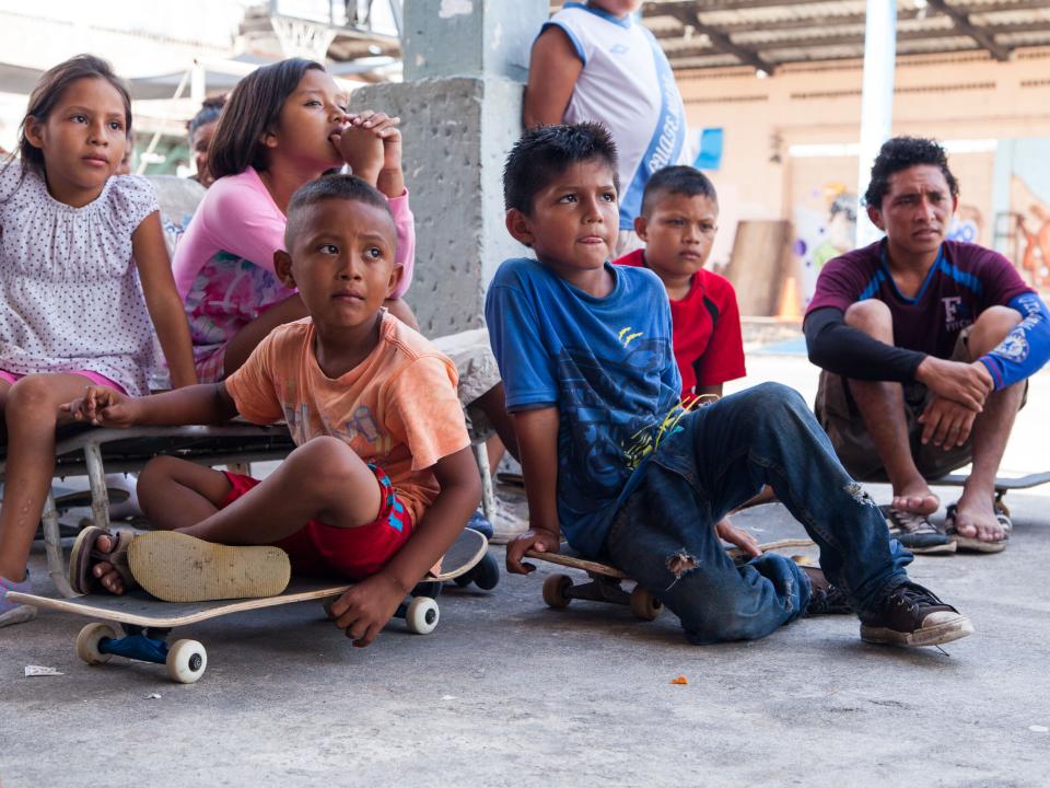 Children sit and listen at a skate park