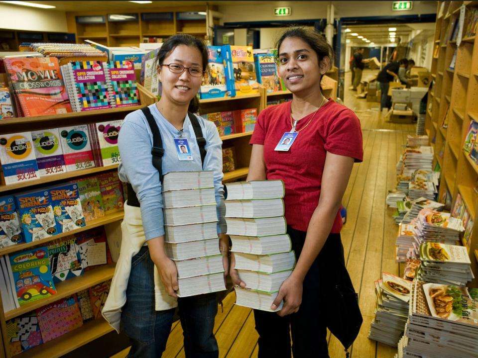 young women stock shelves with books
