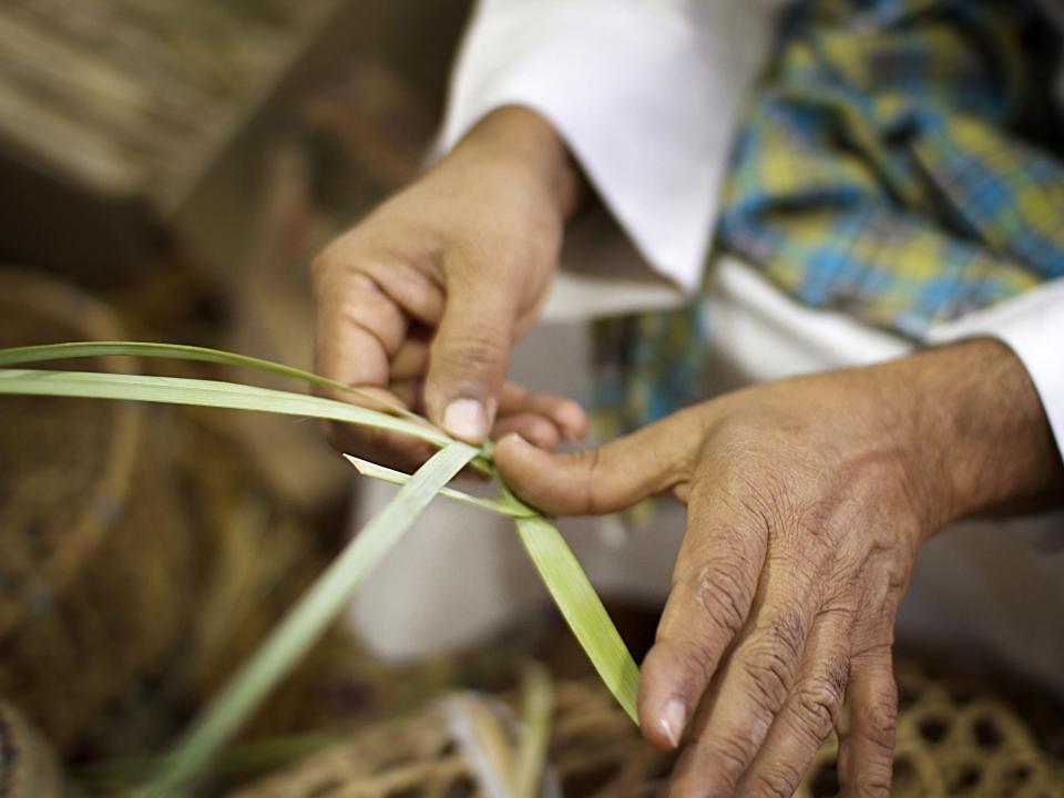Man weaves reed baskets in Bahrain.  
Photo by Kathryn Berry