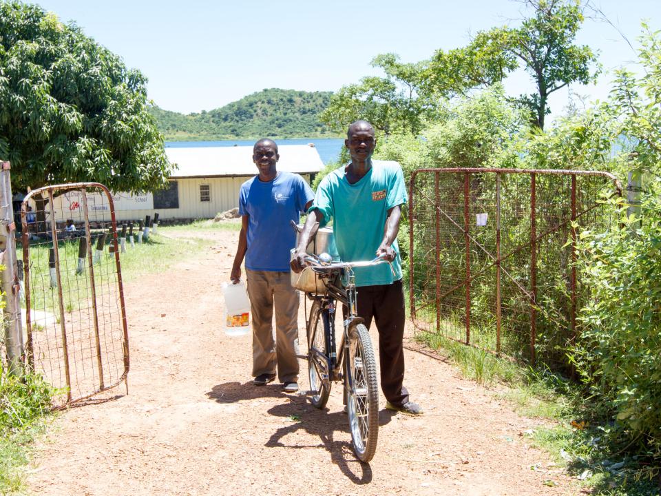 OMers Kaunda, left, and Alex load nshima and water onto a bike to take to the local prison. Three times a week OM Lake Tanganyika team members visit the prison to share the Word of God and provide a meal for the prisoners.