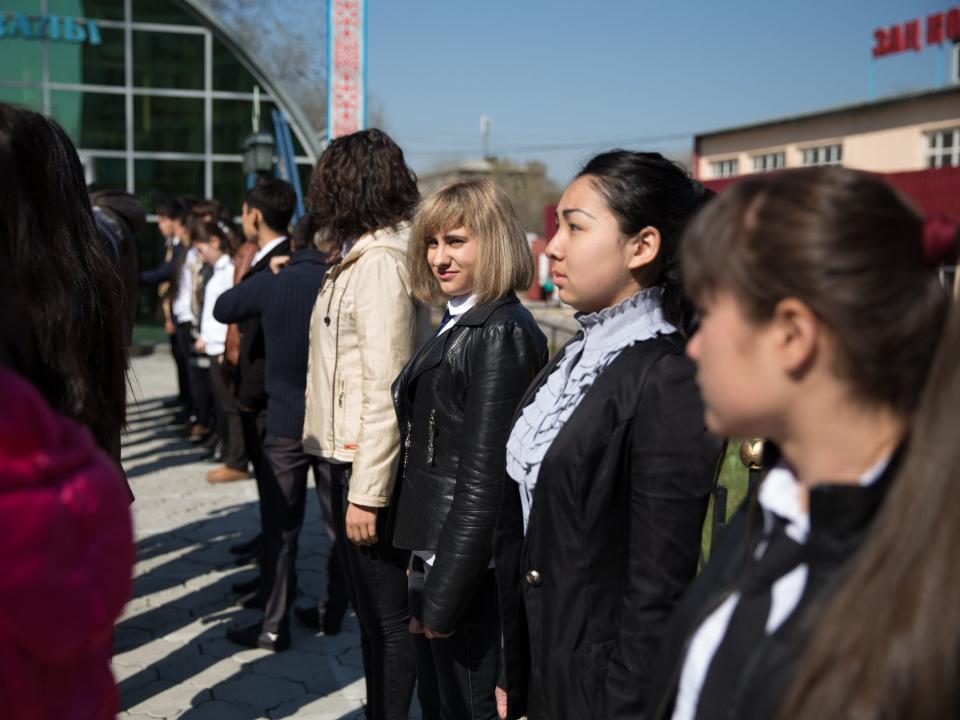 A group of Central Asian university students stand in a line.