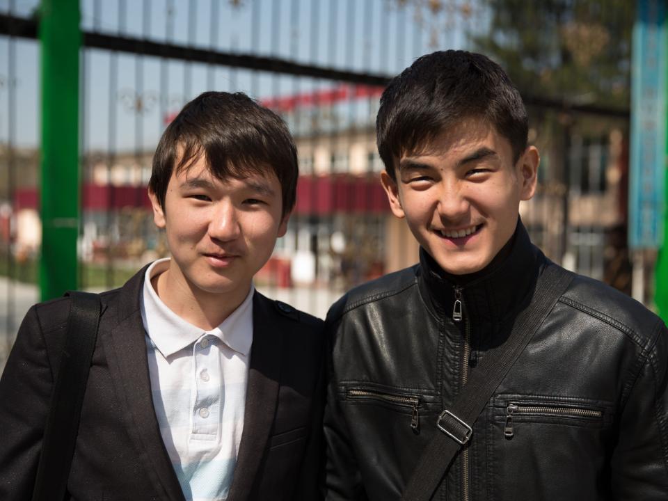 Two male university students in Central Asia smile for the camera.