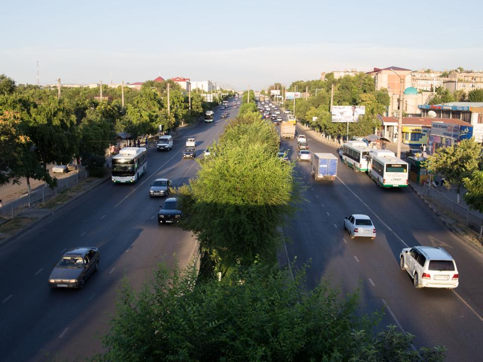 Traffic flows on a wide tree-lined city street in Central Asia.