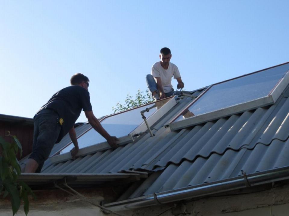 Workers intstall solar panels on a rooftop