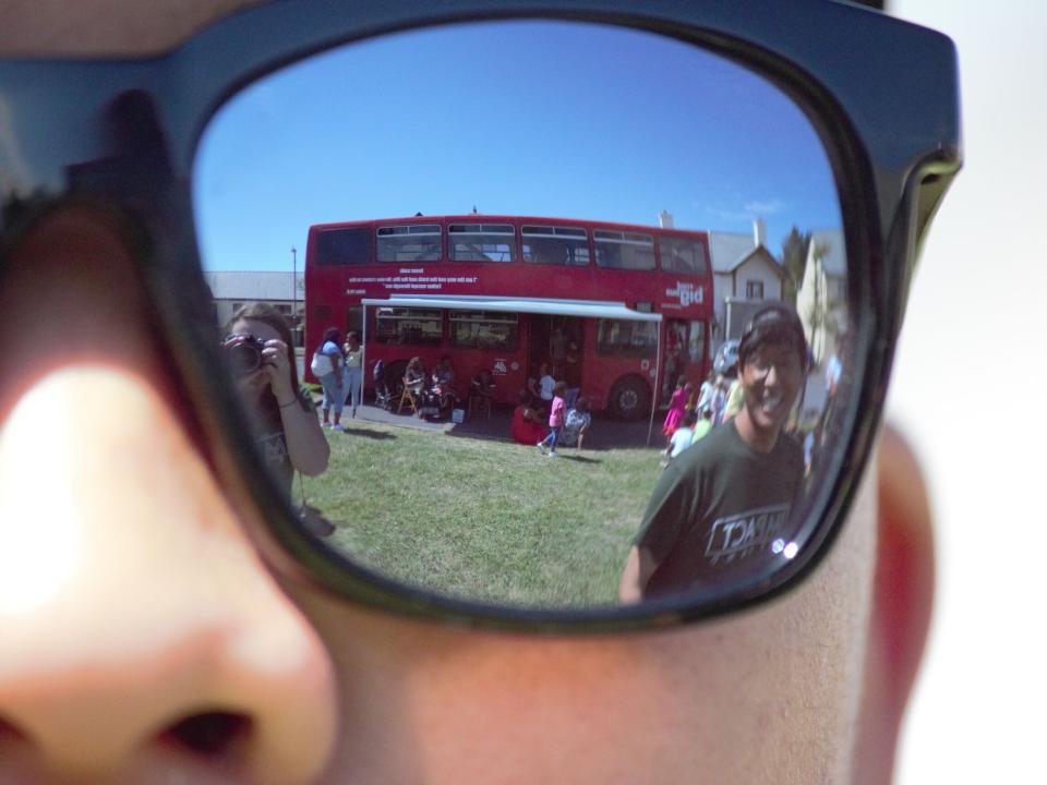 The Big Red Bus is reflected in sunglasses.