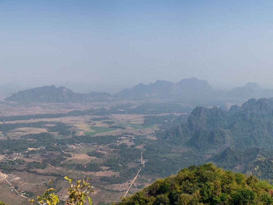 Hpa-an is small city with mountains and fields scattered around it. In the distance you can see a peak adorned with a small Buddhist shrine.