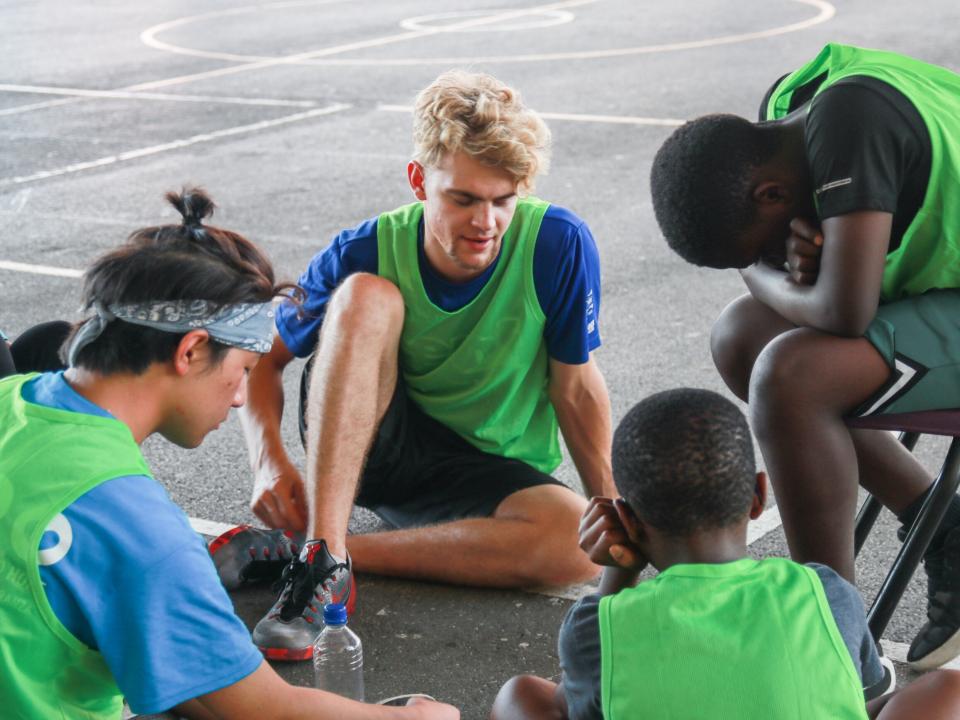 Bridgetown, Barbados :: Liam Packwood (Scotland) prays with teenagers at a church basketball tournament.