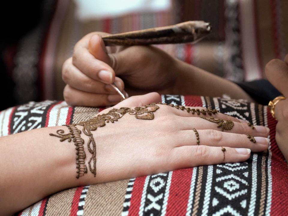 An Arab woman decorates a woman's hand with a henna design. Photo by Jay S.