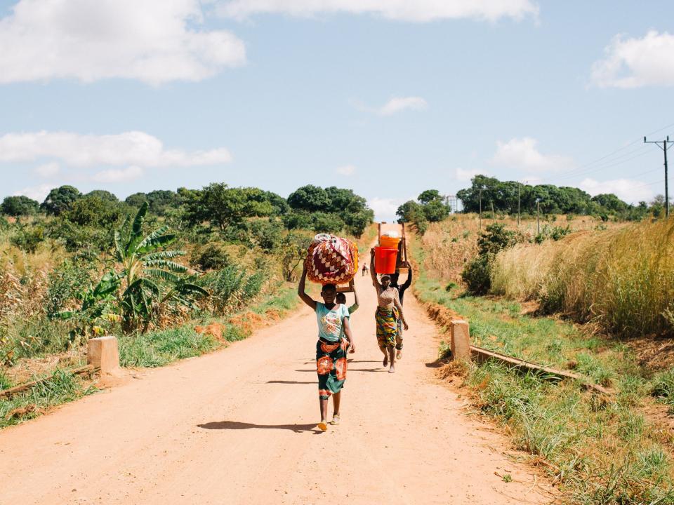 A group of women carry bundles down a road in Mozambique. Photo by Doseong Park.