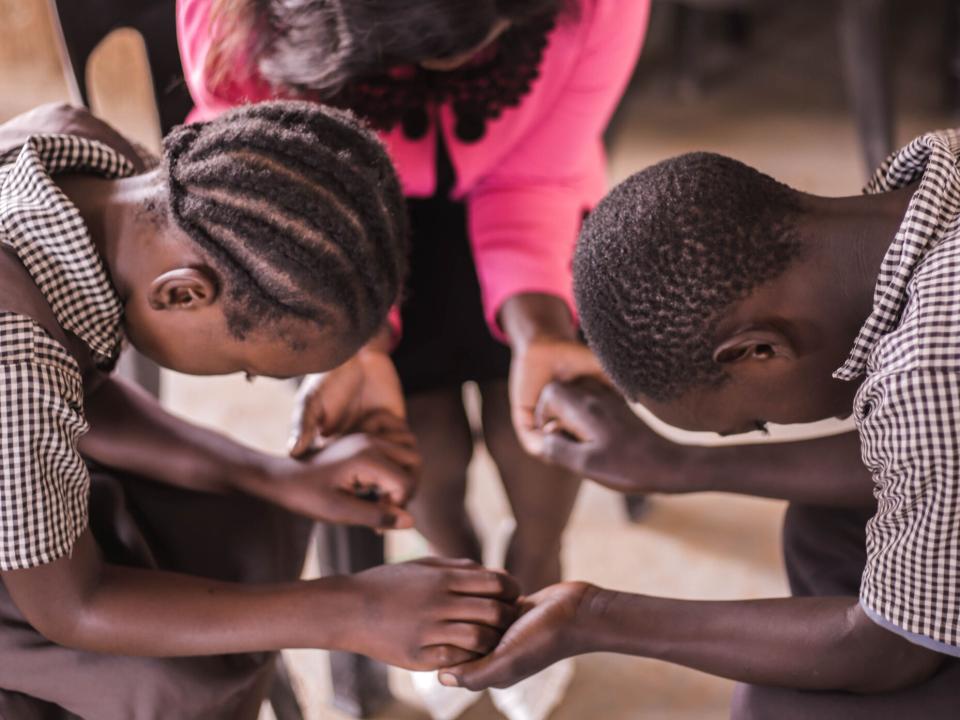 Teacher and students pray together at Makwati School in Kabwe, Zambia.