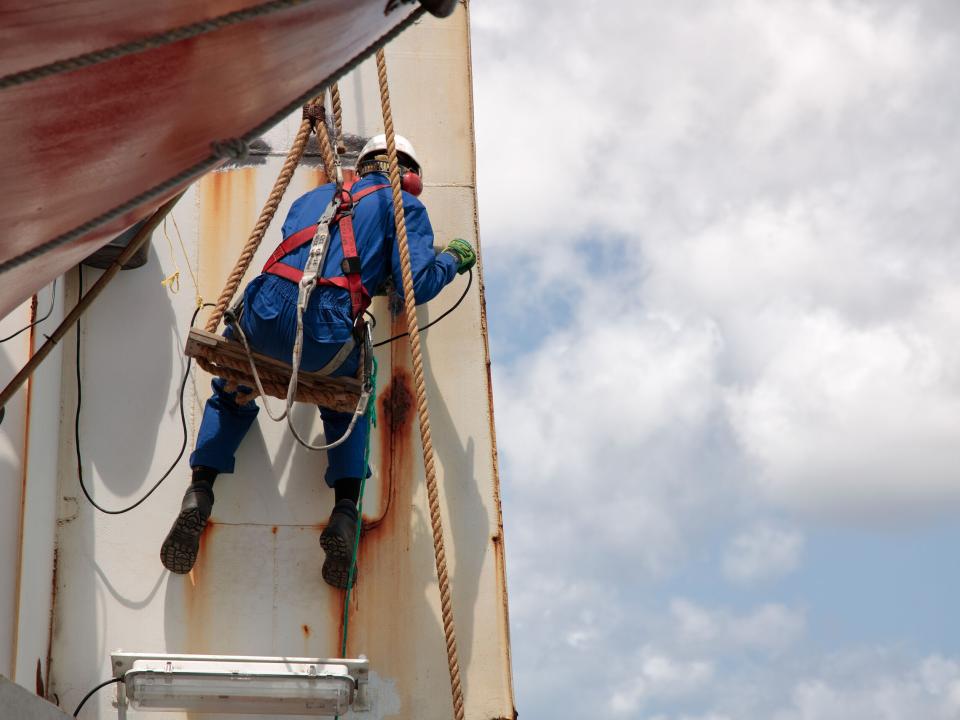 Willemstad, Curaçao :: A crewmember removes rust before the exterior of Logos Hope is repainted for another year.
