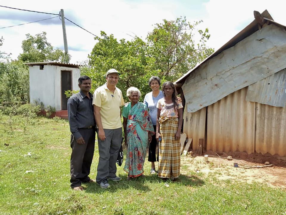 George (in yellow) with his wife Janet (behind in blue) in Sri Lanka visiting the war widows ministry. The woman in the centre of the photo is one of the first widows the ministry helped. After hearing her story from a local pastor (in black), they helped