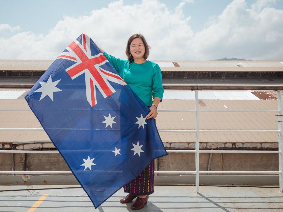 OM Ships :: Frances Win (Australia) shows her Australian flag while wearing the Burmese traditional costume as she grew up in Myanmar (previous Burma) but moved with her family to Australia when she was in he 20s and considers herself Australian.