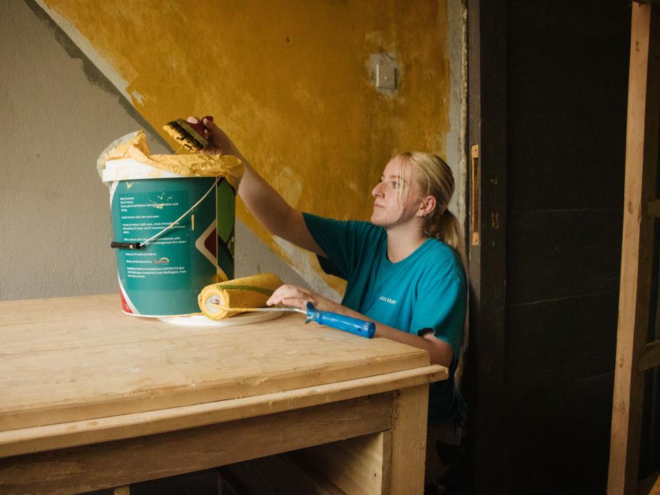 Freetown, Sierra Leone :: Mercedes Corcoran (United Kingdom) paints a wall at the family-focussed facility, All For One Foundation.