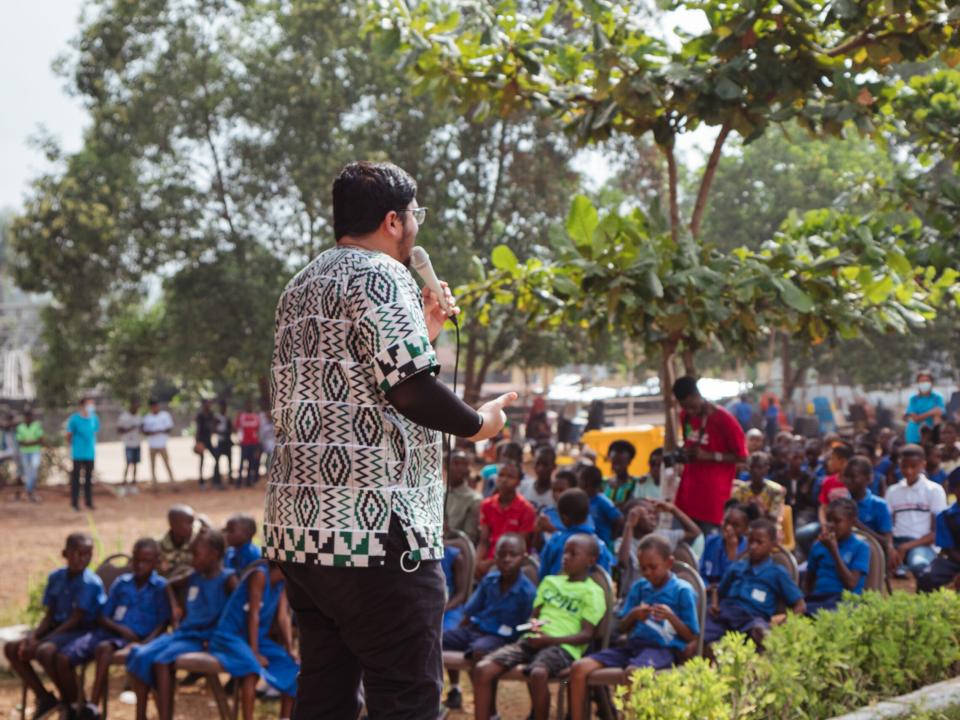 Freetown, Sierra Leone :: Nidhin Sebastian (India) speaks to young people at an event in the grounds of a school.