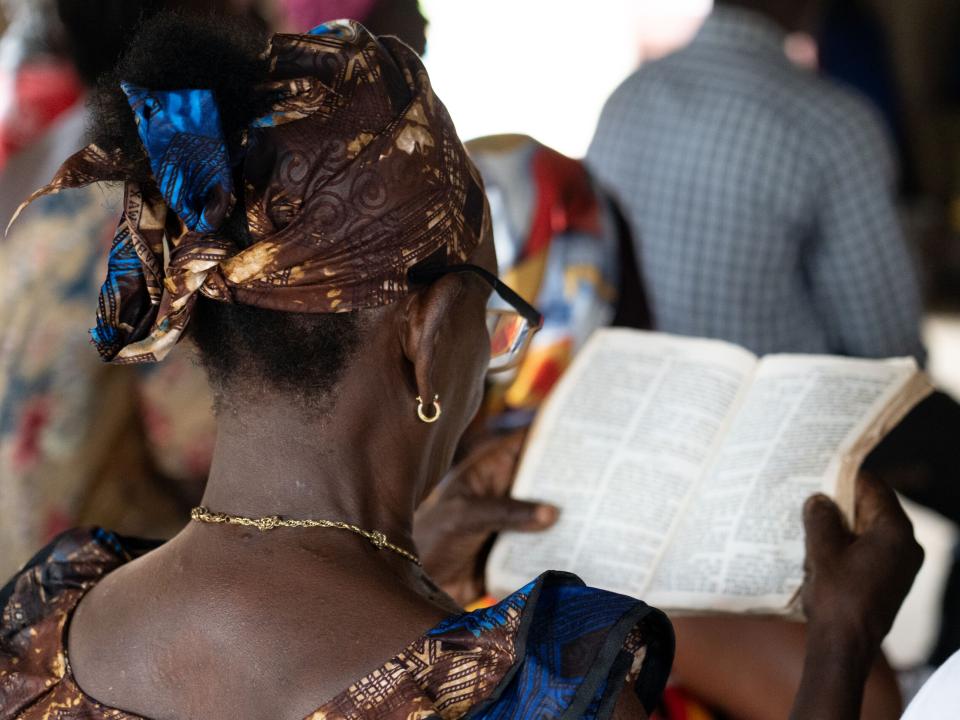 A woman reads her Bible during church in a village in Sierra Leone. Photo by RJ Rempel.