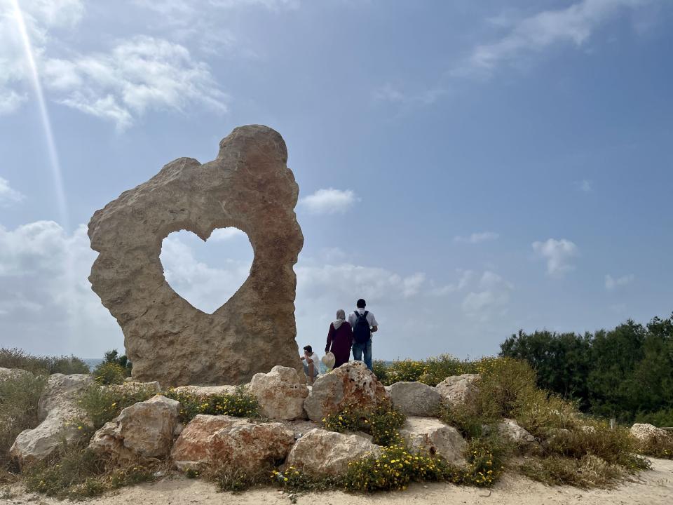 Arab couple by rock with heart cut out in it. Photo by Kate Toretti.