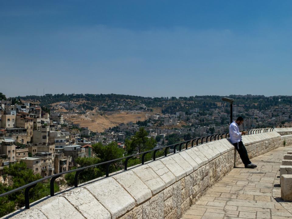 Jewish man praying with Arab town behind him. Photo by Kate Toretti.