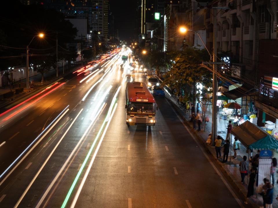 A bus makes a stop at night in Bangkok, Thailand. Photo by RJ Rempel.
