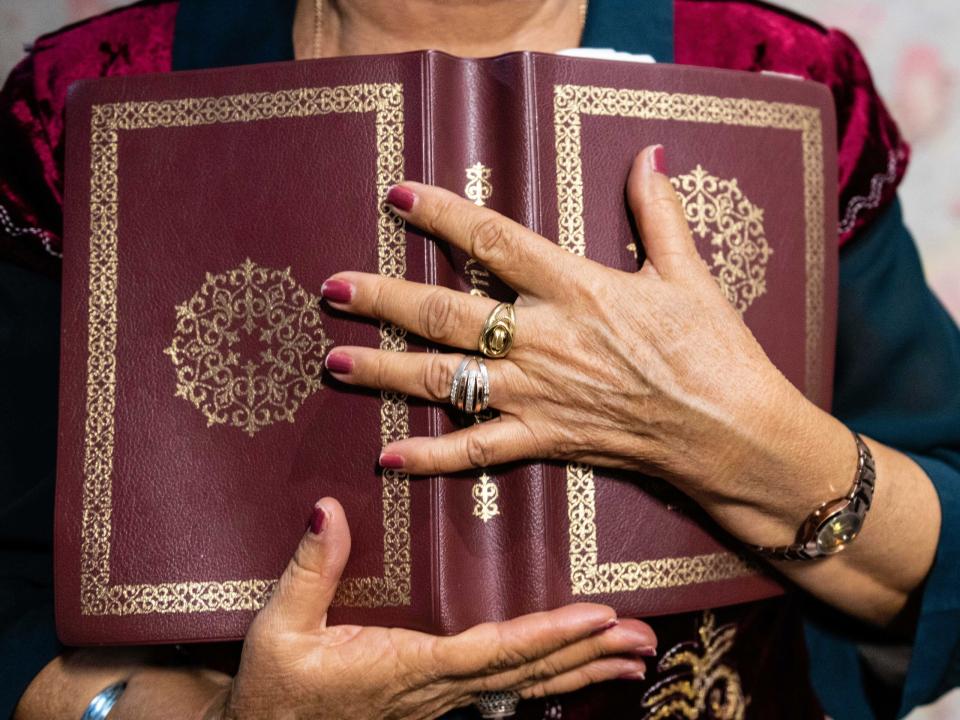 Central Asian woman holds a decorated Bible close to her chest. Photo by Adam Hagy.