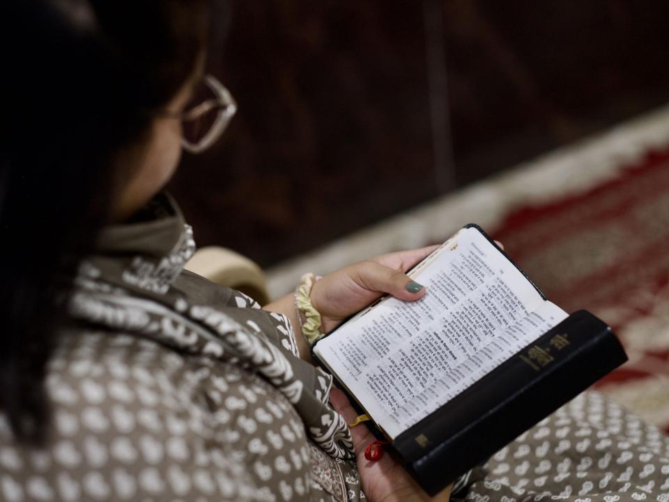 A woman reading her Bible during a church service in South Asia. Photo by Hadley Toweel.