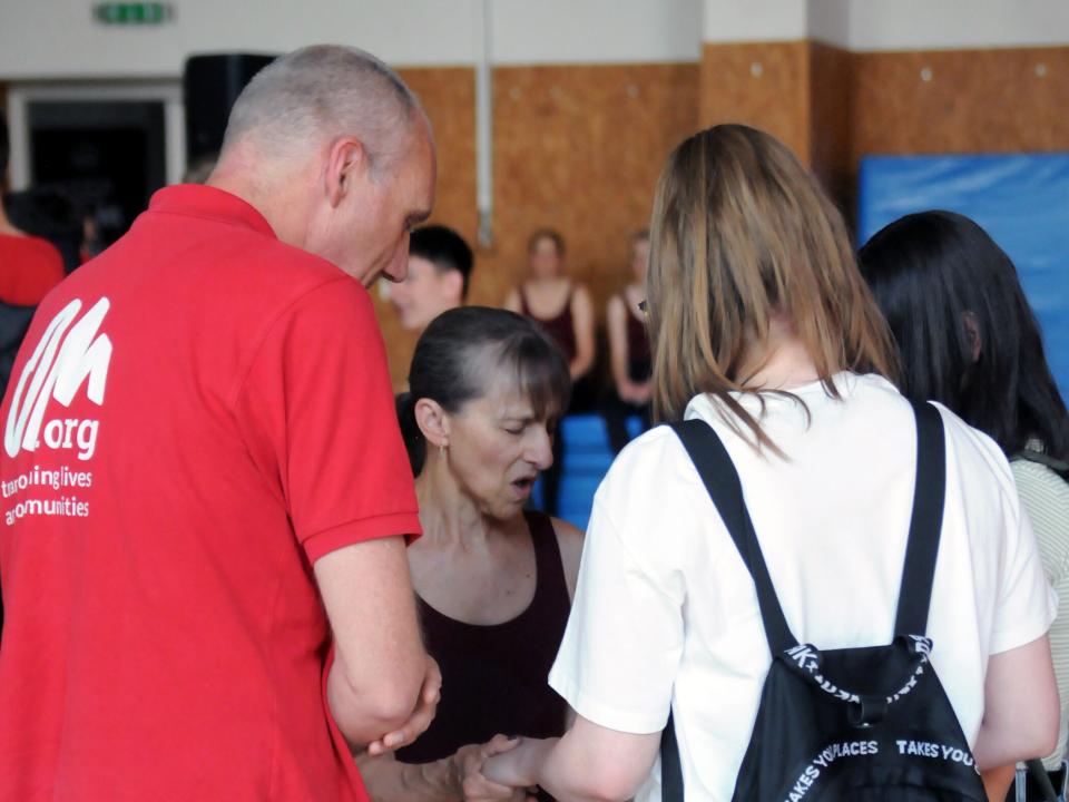 A dancer on the Bill Drake Band Hope tour in Hungary prays with two students to receive Christ after a concert. Photo by Photo-guy / Guy Williams.