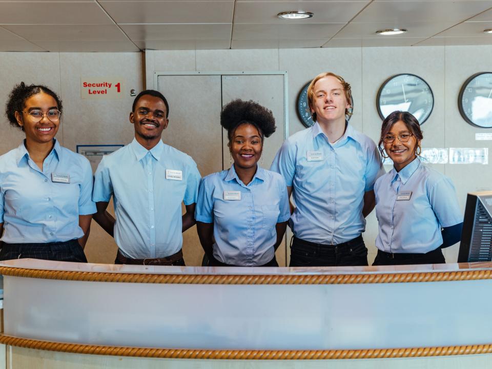 Ships :: Centered, Esnart (Zambia), smiles alongside her service desk team on board Logos Hope.