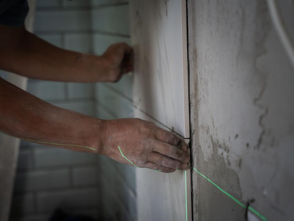 A man lines up tiles at a construction site. Photo by RJ Rempel.