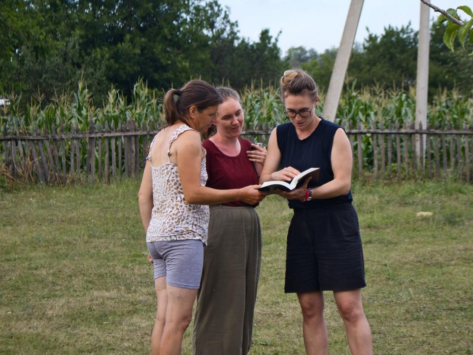 A short-termer and OM team member share the Bible with a woman in rural Moldova.