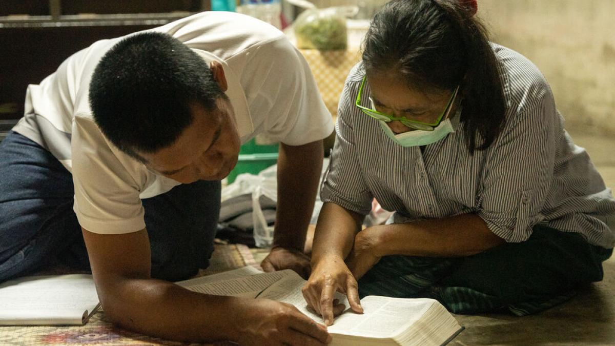 uomo donna tailandese piegati per terra a leggere una Bibbia insieme