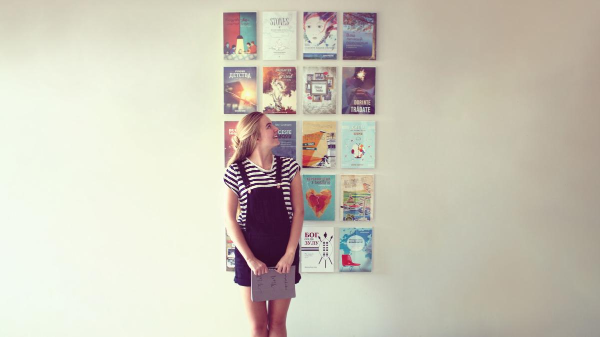 Artist showing book covers displayed on a wall