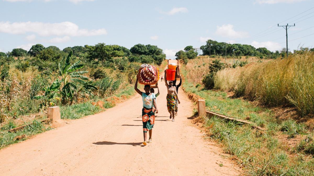 A group of women carry bundles down a road in Mozambique. Photo by Doseong Park.