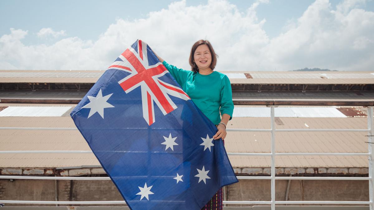 OM Ships :: Frances Win (Australia) shows her Australian flag while wearing the Burmese traditional costume as she grew up in Myanmar (previous Burma) but moved with her family to Australia when she was in he 20s and considers herself Australian.