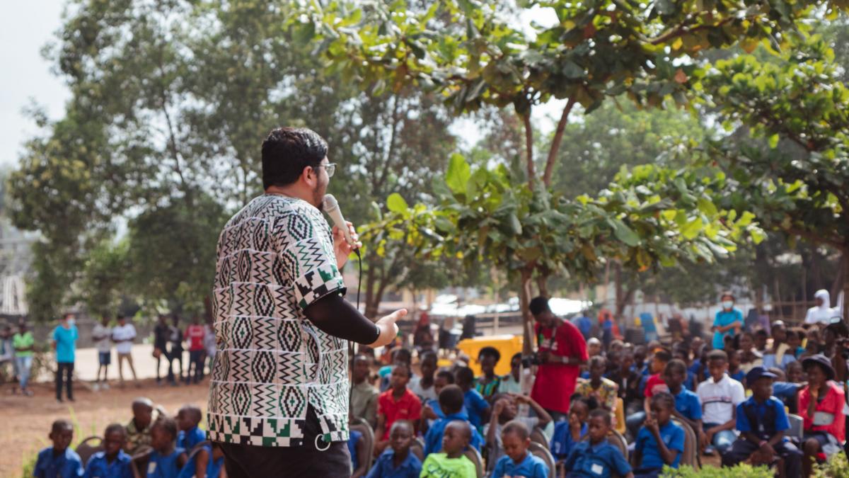 Freetown, Sierra Leone :: Nidhin Sebastian (India) speaks to young people at an event in the grounds of a school.