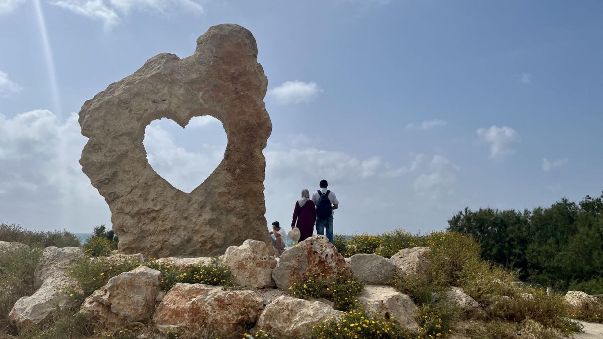 Arab couple by rock with heart cut out in it. Photo by Kate Toretti.