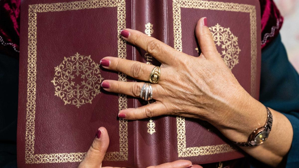 Central Asian woman holds a decorated Bible close to her chest. Photo by Adam Hagy.