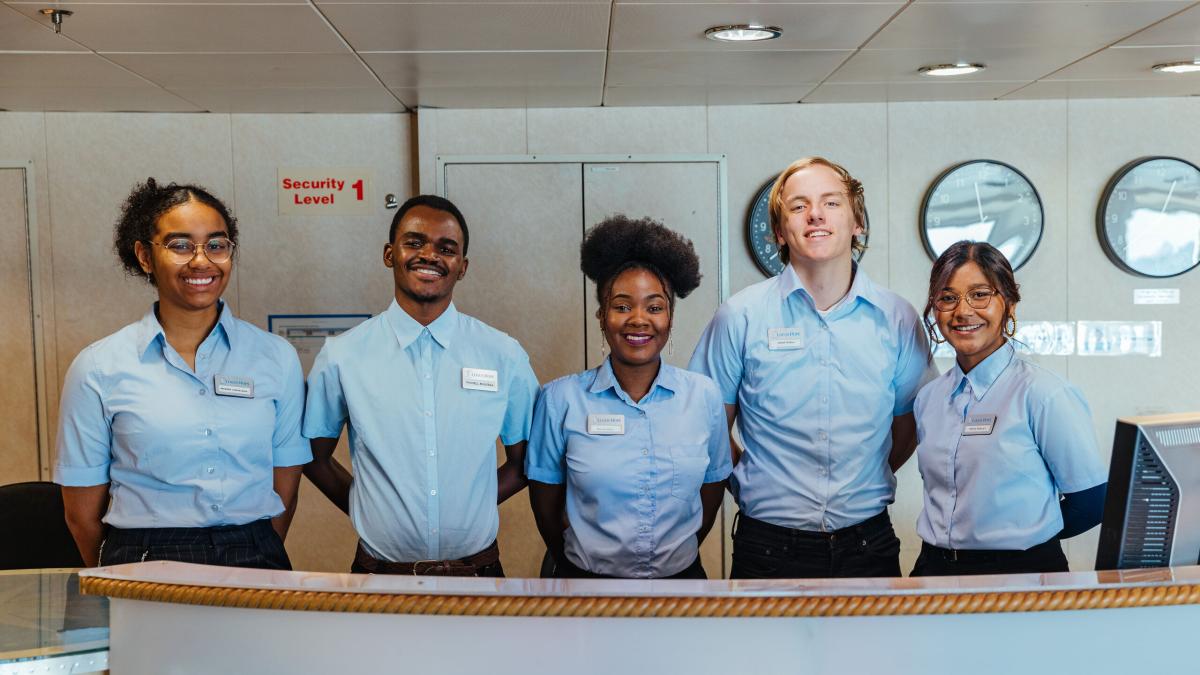 Ships :: Centered, Esnart (Zambia), smiles alongside her service desk team on board Logos Hope.