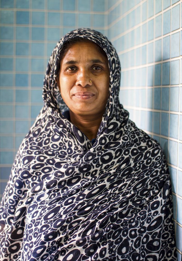 Frau aus der arabischen Halbinsel in schwarz/weißem Schleier vor gefließter Wand