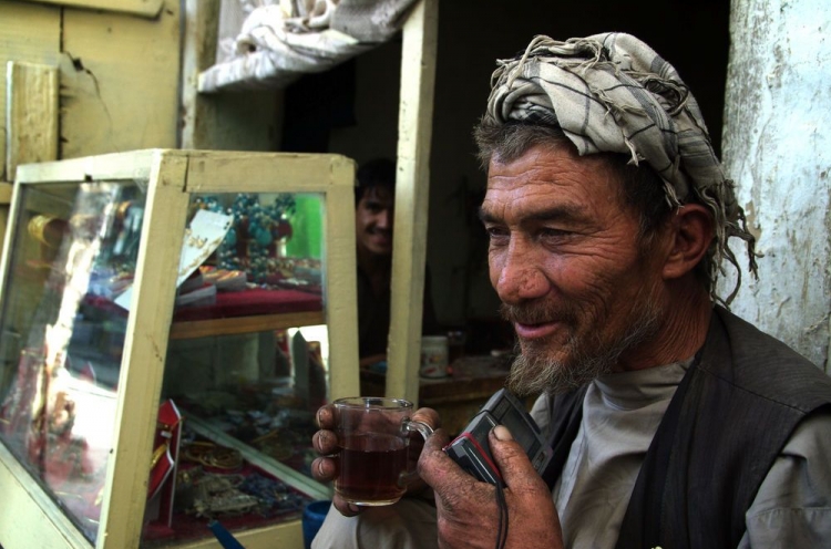 Mann in Afghanistan mit kleinem Radio und Teetasse