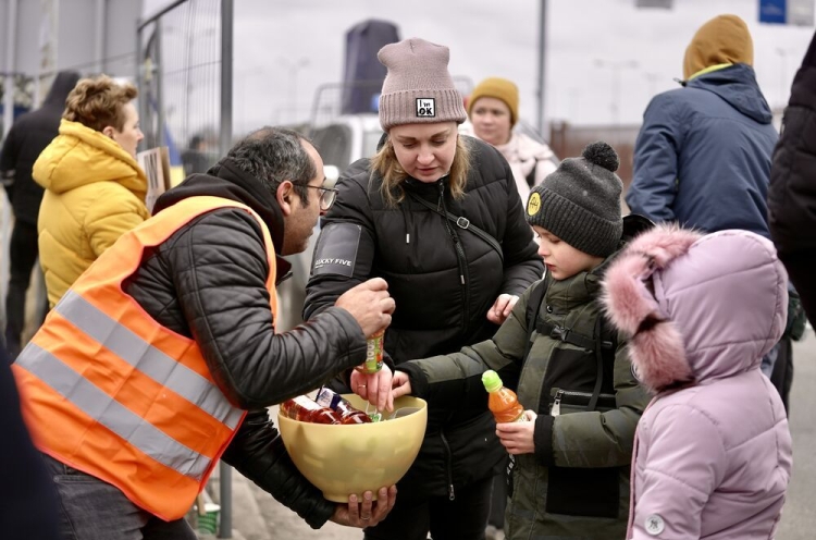 Mitarbeiter gibt an der polnisch-ukrainischen Grenze Hilfsgüter an Mutter mit zwei Kindern