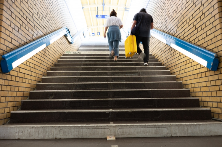 Zwei Personen steigen die Stufen einer U-Bahn-Station hoch ins Licht
