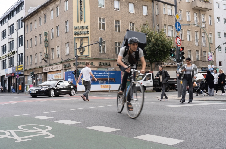 Fahrradkurier fährt an einer belebten Kreuzung in Berlin um die Kurve