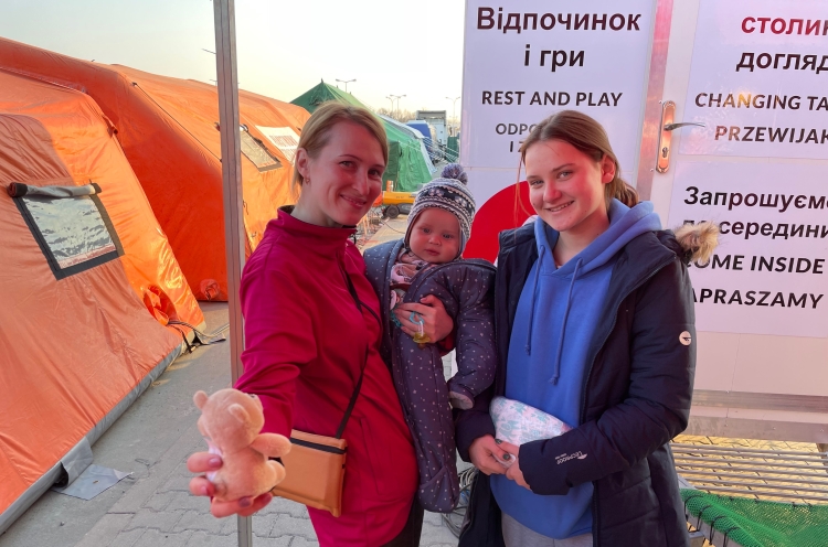 Lächelnde Frauen mit Baby beim Hilfstand von OM in Polen