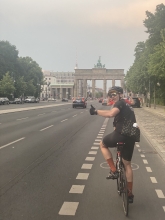Radfahrer beim Corona Ride 2021 vor dem Brandenburger Tor. Blickt über die Schulter und hebt den Daumen.